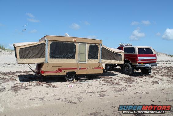 1990 Ford Bronco with pop-up camper on a sandy beach