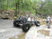 1967 Ford Mustang - A custom-built buggy with oversized tires is shown traversing a rocky, wet terrain with onlookers nearby.