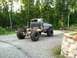 1983 Chevrolet C/K Pickup - Modified pickup truck with oversized tires sits on a gravel lot, chassis visible at the rear.