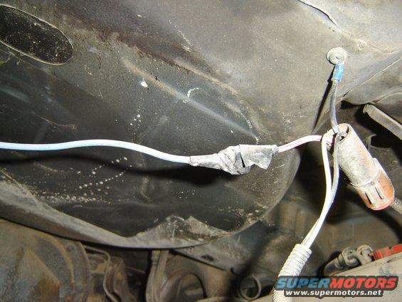 Close-up of a taped automotive wiring harness with connectors under a vehicle