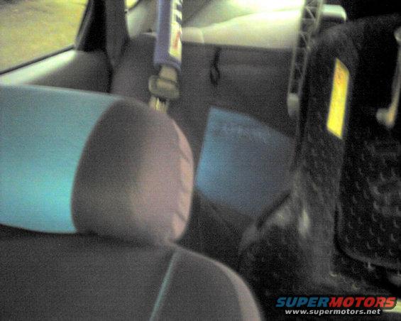 Car interior showing rear seats, headrests, and a yellow warning sticker on the right side panel