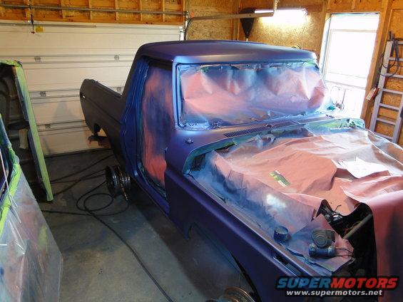 Purple pickup truck in garage with fresh paint, hood and doors covered