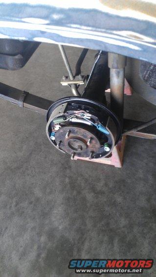 Close-up of a car's rear drum brake assembly with leaf springs and shock absorber visible