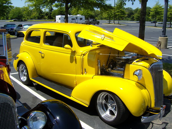 Yellow sedan with hood open, chrome wheels, parked in a lot