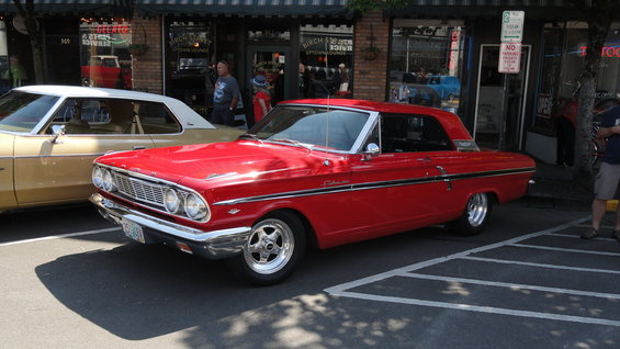 Red 1964 Ford Fairlane parked next to a tan car on a street