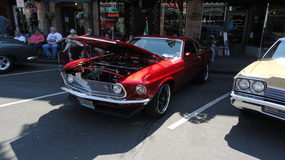 Red 1969 coupe with hood open, parked next to a tan car