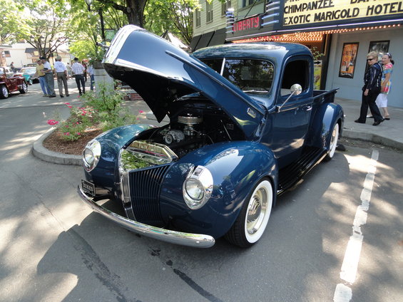 Blue pickup truck with hood open, showing engine. Whitewall tires, chrome grille, and bumper