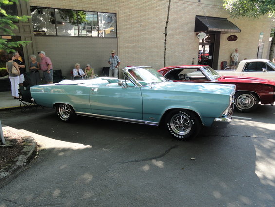 Light blue convertible with chrome wheels, parked next to a red car