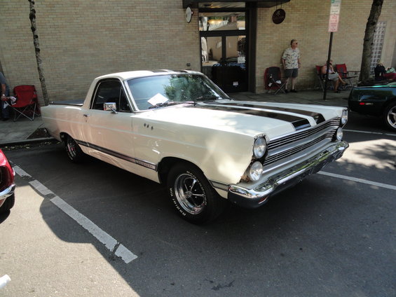 White Ford Ranchero with black racing stripes parked on asphalt