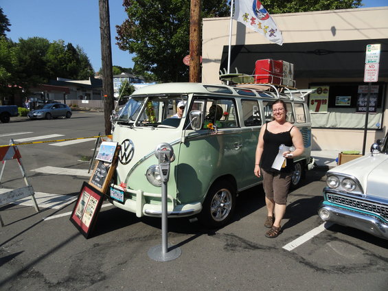 Green and white Volkswagen Type 2 panel van with surfboards and luggage on roof