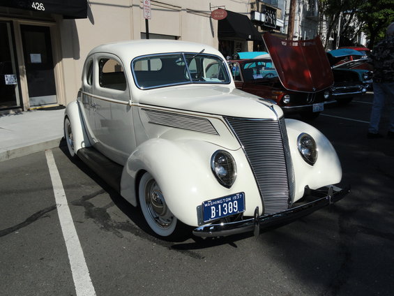 White 1937 coupe with a prominent chrome grille and whitewall tires, parked on asphalt