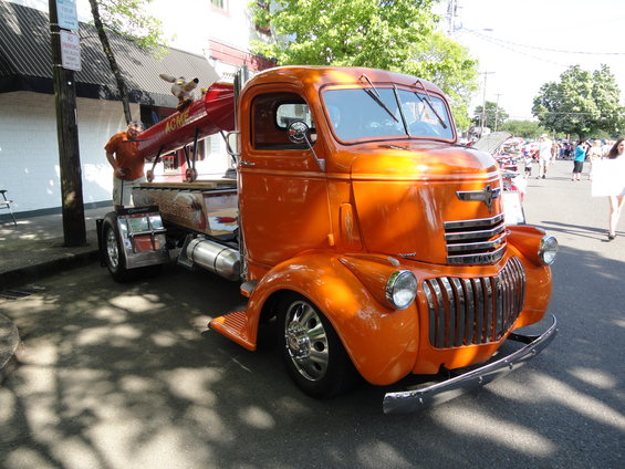 Orange tow truck with a cartoon character on the boom, parked on a street