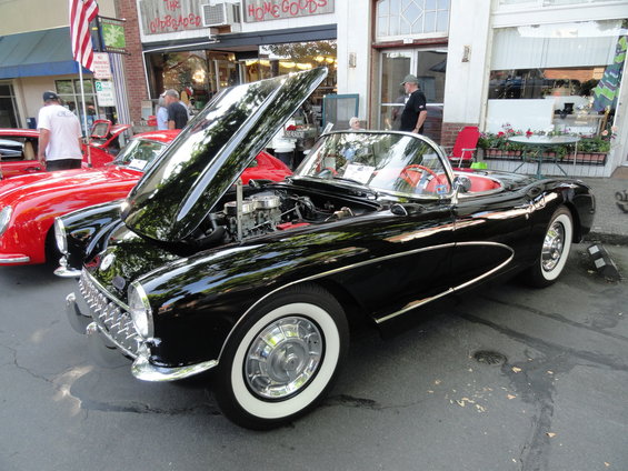 Black 1956 Corvette convertible with hood open, red interior, whitewall tires
