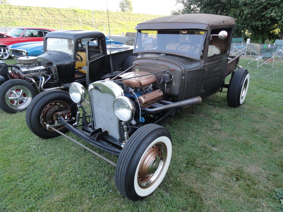 Rusty hot rod pickup truck with exposed engine, chrome grille, and whitewall tires