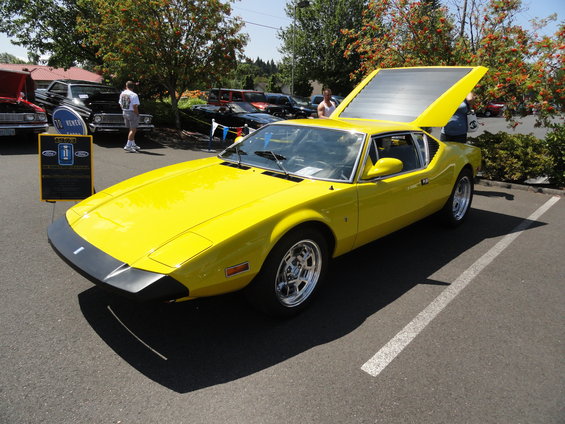 yellow sports car with hood open, parked at an outdoor event
