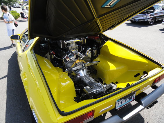 Yellow sports car with hood open showing a chrome-detailed engine and a license plate reading '73 PANT'