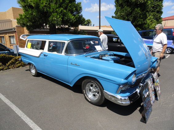 Blue and white 1957 Ford station wagon, hood open, with chrome trim and aftermarket wheels