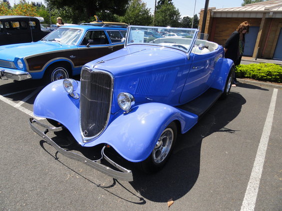 Blue 1934 Ford hot rod convertible parked next to a blue and wood-paneled station wagon