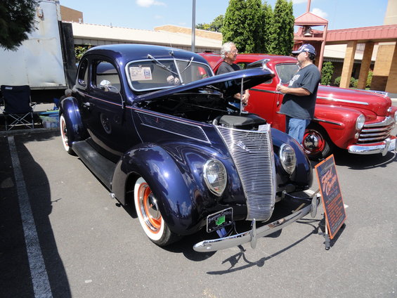 Dark blue 1939 Ford coupe with hood open, whitewall tires, and a sign that reads "Ford Coupe"