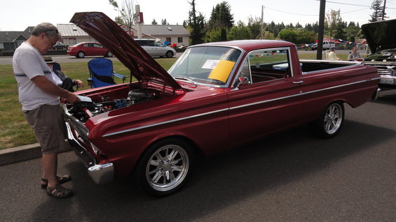 man looking at engine of red 1964 Ford Falcon Ranchero