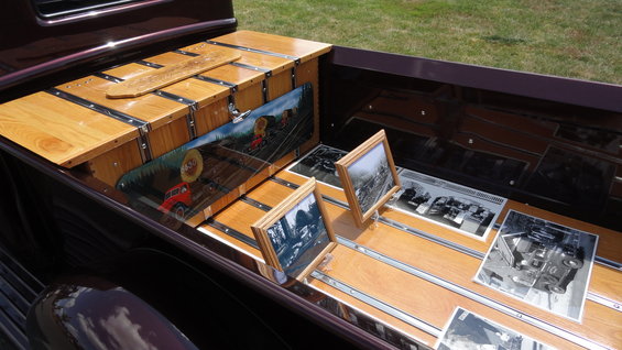 Pickup truck bed with polished wood, chrome trim, framed photos, and a mural of wagons