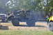 1959 Kenworth W900A - A military truck with a loader arm is parked on a grassy field next to other vehicles.