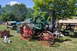1959 Kenworth W900A - A vintage steam tractor with prominent red wheels and a green flywheel is displayed outdoors, with other machinery and tents in the backgro…