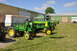 1959 Kenworth W900A - Several green John Deere tractors are parked on a grassy field next to a building.