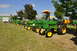1959 Kenworth W900A - Several John Deere tractors are displayed in a grassy field under a blue sky with some trees and buildings in the background.