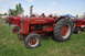 1959 Kenworth W900A - Several red tractors are lined up on a grassy field under a partly cloudy sky.