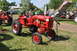 1959 Kenworth W900A - A red Farmall tractor is displayed at an outdoor event with other farm equipment in the background.
