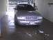 2003 Ford Crown Victoria - A silver 2003 Ford Crown Victoria is parked head-on in a car wash bay, its front grille and license plate clearly visible.