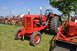 1959 Kenworth W900A - A red tractor is displayed outdoors on a sunny day, with a line of similar vehicles visible behind it.