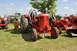 1959 Kenworth W900A - A red Massey-Harris tractor is displayed outdoors at an event with other farm equipment.