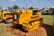 1959 Kenworth W900A - A yellow caterpillar tractor is parked on wood shavings at an outdoor event with other vehicles in the background.