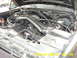 1988 Ford Bronco - The engine bay of a vehicle is shown with the hood open, revealing the engine components and associated wiring and hoses.