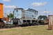 1959 Kenworth W900A - A weathered blue diesel locomotive is parked on a railway track next to an orange rail car.