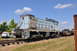 1959 Kenworth W900A - A light blue train engine, marked with the number 36, sits on tracks under a blue sky with scattered clouds.