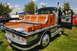 1959 Kenworth W900A - A custom flatbed truck with a polished wooden bed and chrome trim is parked on grass with other vehicles nearby.