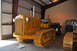 1959 Kenworth W900A - A yellow Caterpillar Sixty Five tractor is parked inside a building with other equipment visible.