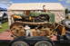 1959 Kenworth W900A - A green crawler tractor with extensive rust on its tracks is parked on a trailer, with a person visible working beneath it.