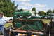 1959 Kenworth W900A - A green crawler tractor is loaded onto a trailer, with a man and other vehicles in the background.