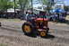 1959 Kenworth W900A - A man drives a red Gibson tractor with yellow wheels during an event, with spectators watching.