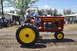 1959 Kenworth W900A - A man drives a red Gibson tractor with yellow wheels and the number 72 on its side, during an event.