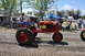 1959 Kenworth W900A - A red tractor is driven by a man past spectators at an outdoor event.