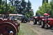 1959 Kenworth W900A - Two red tractors, one with a passenger holding a red umbrella, drive down a dirt road during a parade at the Oregon Steam Up event.