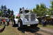 1959 Kenworth W900A - A large white Big Bud tractor is displayed at an outdoor event, with an American flag attached to its cab.