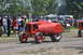 1959 Kenworth W900A - A red tractor with a driver is on a dirt path, with spectators in the background.