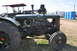 1959 Kenworth W900A - A Rumely tractor is parked on grass with other vehicles and portable toilets in the background.