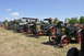 1959 Kenworth W900A - Several vintage steam tractors are lined up on a grassy field under a clear blue sky.